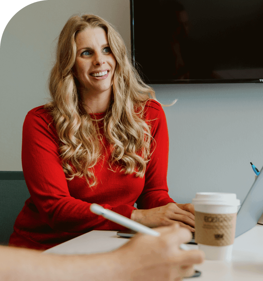 woman in red shirt happily working on a laptop